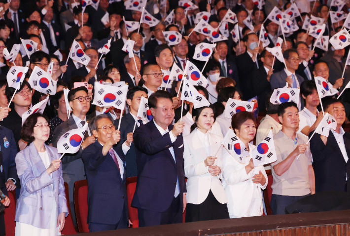 윤석열 대통령과 김건희 여사가 15일 서울 종로구 세종문화회관에서 열린 제79주년 광복절 경축식에서 이동일 순국선열유족회장 등 참석자들과 함께 태극기를 흔들고 있다. 연합뉴스