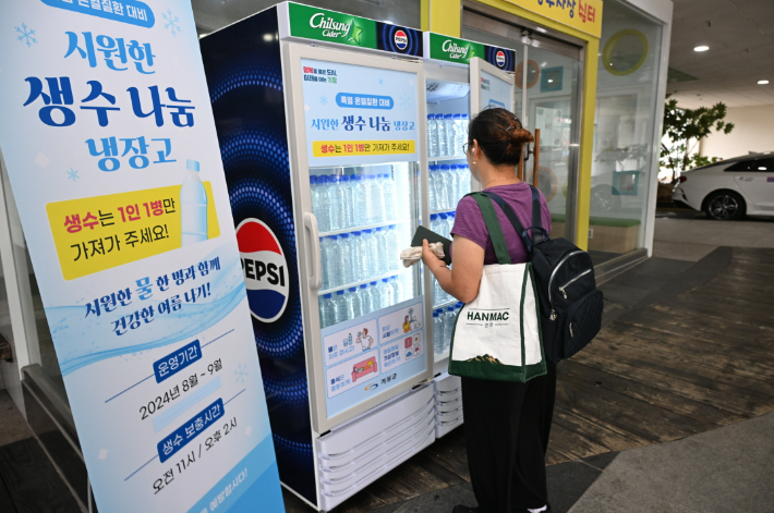 한 시민이 부산 기장군 기장시장 공영주차장에 설치된 무료 생수 나눔 냉장고를 이용하고 있다. 부산 기장군 제공 