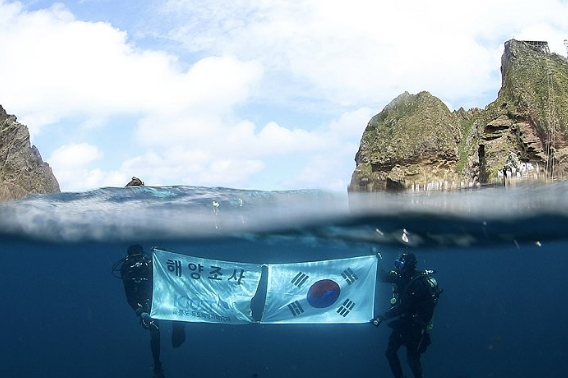 독도 일대를 조사 중인 한국해양과학기술원 울릉도독도해양연구기지 직원들이 광복절을 앞둔 14일 독도의 하늘과 바다를 배경으로 태극기를 펼쳐 보이고 있다. 울릉도독도해양연구기지 제공