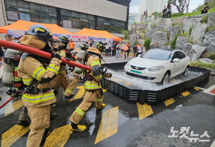 소방대원들이 배터리 냉각을 위해 전기차를 이동식 침수조 안으로 옮긴 후 차량을 향해 물을 분사하고 있다. 김혜민 기자 