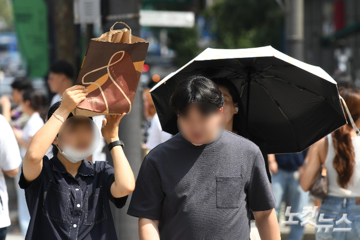 서울에 사상 첫 '9월 폭염경보'가 내려진 11일 서울 광화문사거리에서 한 시민이 쇼핑백으로 햇빛을 가리고 있다. 박종민 기자