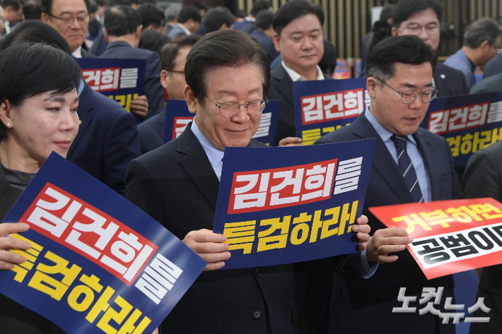 더불어민주당 이재명 대표가 4일 서울 여의도 국회에서 열린 의원총회에서 피켓을 살펴보며 미소짓고 있다. 윤창원 기자