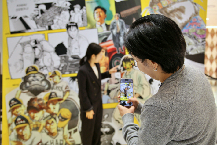 광주신세계 방문객들이 허영만 화백 작품으로 구성된 아트월에서 인증샷을 찍고 있다. 광주신세계 제공