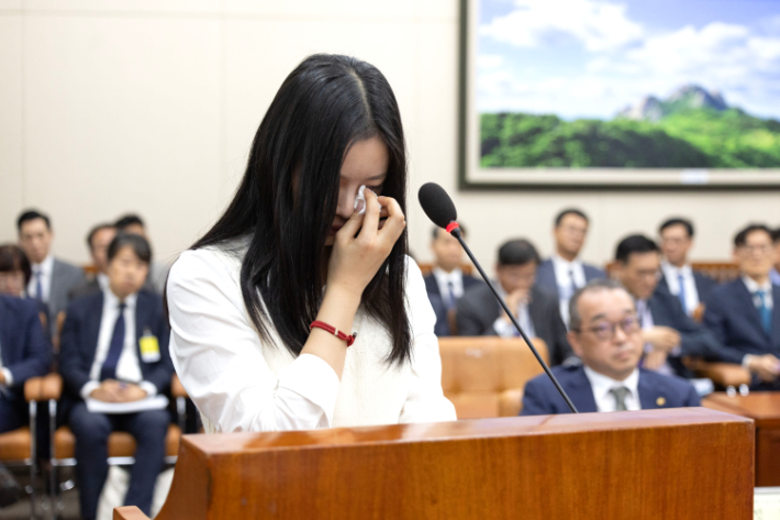 뉴진스 하니가 15일 서울 여의도 국회에서 열린 환경노동위원회 국정감사에서 눈물을 닦고 있다. 연합뉴스