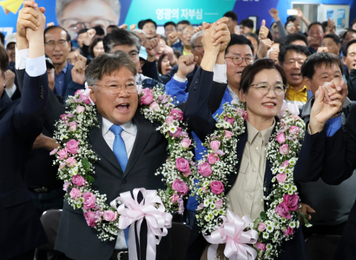 16일 전남 영광군수 재보궐선거에서 당선이 확실시된 더불어민주당 장세일 후보가 배우자 정수미 씨와 화환을 목에 걸고 지지자들에게 인사하고 있다. 연합뉴스