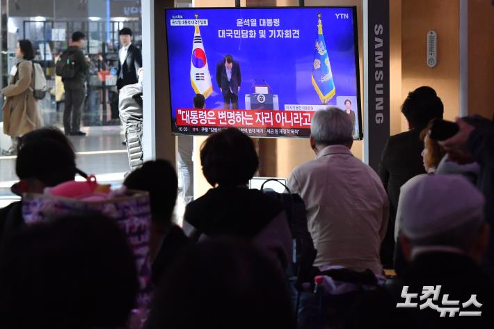 고개 숙인 윤석열 대통령 지켜보는 시민들