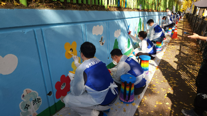 삼성전자 임직원들이 12일 수원시 권선구 구운초등학교에서 벽화 그리기 봉사 활동에 참여하고 있다. 삼성전자 제공