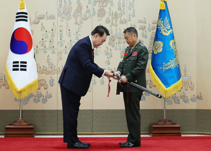 윤석열 대통령이 27일 서울 용산 대통령실 청사에서 열린 중장 진급·보직 신고 및 삼정검 수치 수여식에서 주일석 해병대사령관의 삼정검에 수치를 달아주고 있다. 연합뉴스