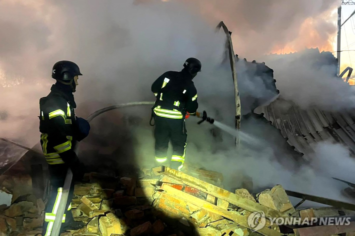 (AFP=연합뉴스) 우크라이나 서부 루츠크의 미사일 피해 현장에서 소방 요원들이 진화 작업을 벌이고 있다. [우크라이나 소방 당국 사진 제공] 연합뉴스