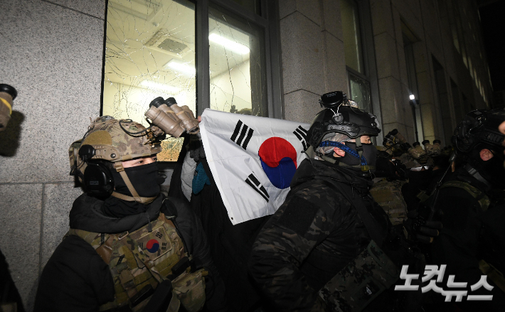 윤석열 대통령이 3일 밤 비상계엄을 선포한 가운데 4일 새벽 계엄군이 서울 여의도 국회 경내로 진입, 태극기를 든 시민이 고함치고 있다. 박종민 기자