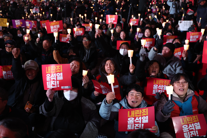 4일 오후 서울 동화면세점 앞에서 열린 '내란죄 윤석열 퇴진! 시민촛불'에서 전국민주노동조합총연맹을 비롯한 참석자들이 촛불을 들어 보이며 구호를 외치고 있다. 연합뉴스