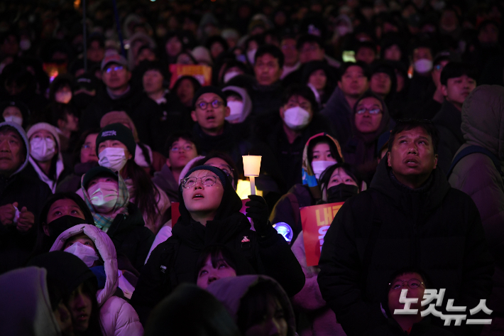 윤석열 대통령 탄핵소추안이 본회의에 상정된 7일 서울 여의도 국회 앞에서 시민들이 중계되는 국회의사당 내부 화면을 지켜보고 있다. 박종민 기자