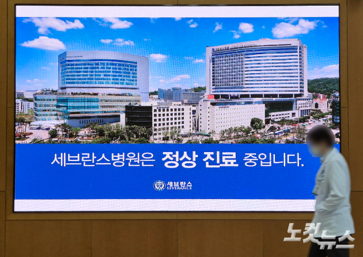 세브란스병원 교수들이 무기한 휴진에 돌입한 6월 27일 서울 서대문구 세브란스병원 전광판 앞을 한 의료진이 지나가고 있다. 황진환 기자