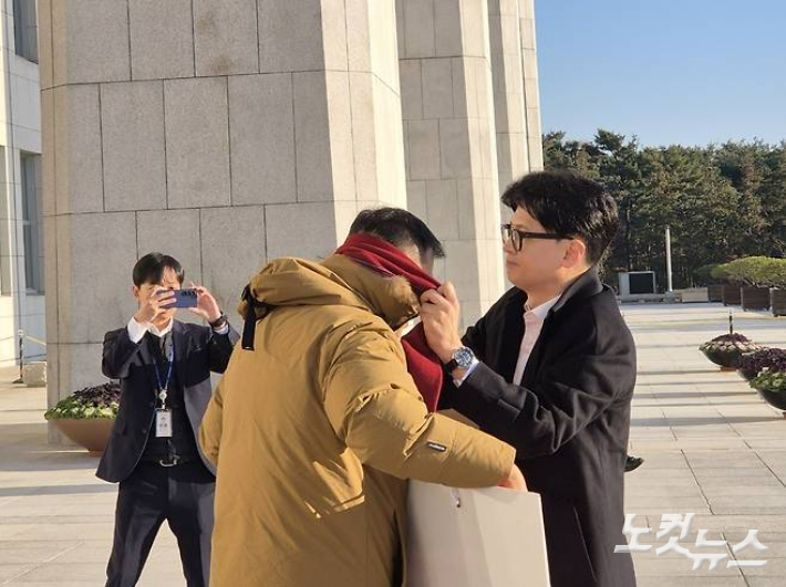 14일 오전 한동훈 국민의힘 대표가 국회 본청에 출근하다가 탄핵 찬성 1인 시위 중인 김상욱 국민의힘 의원을 만나 자신의 목도리를 둘러주고 있다. 국민의힘 제공