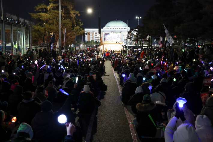 '윤석열 즉각 퇴진·사회대개혁 비상행동'이 13일 오후 서울 영등포구 국회의사당 인근에서 연 탄핵소추안 국회 통과 촉구 촛불집회에서 참가자들이 응원봉을 들고 구호를 외치고 있다. 연합뉴스