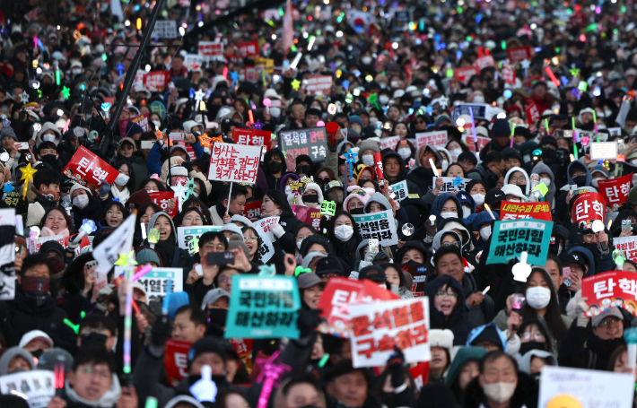 윤석열 대통령 탄핵소추안이 가결된 14일 서울 여의도 국회 앞에서 열린 집회에 참석한 시민들이 환호하고 있다. 연합뉴스