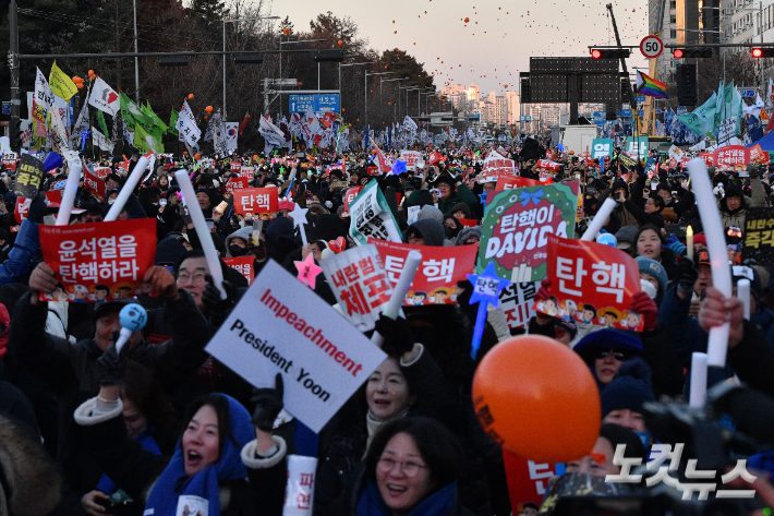 윤석열 대통령 탄핵소추안이 가결된 지난 14일 서울 여의도 국회 앞에서 열린 촛불집회에 참석한 시민들이 탄핵이 가결되자 환호하고 있다. 류영주 기자