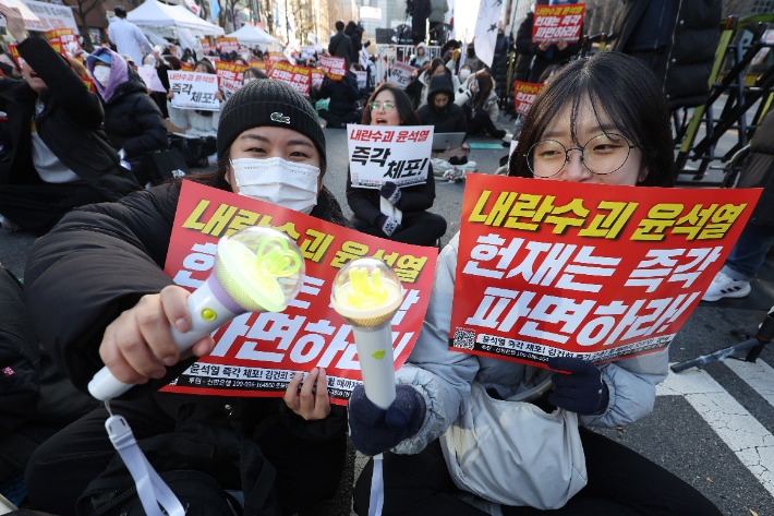 지난 15일 오후 서울 종로구 광화문광장 인근에서 시민단체 촛불행동 주최로 열린 '내란수괴 윤석열 헌재는 즉각 파면하라' 집회에서 참가자들이 윤석열 대통령의 체포·파면을 촉구하는 손팻말과 응원봉을 들고 있다. 연합뉴스