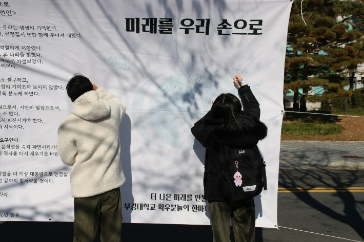 18일 국립부경대학교 학생들이 시국선언을 발표한 뒤 펼침막에 대통령 탄핵을 촉구하는 내용의 글을 자유롭게 적고 있다. 국립부경대학교 재학생 제공 