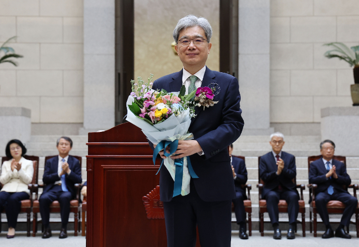 김상환 대법관이 27일 서울 서초구 대법원에서 열린 퇴임식에서 직원에게 꽃다발을 받은 뒤 기념촬영을 하고 있다. 연합뉴스