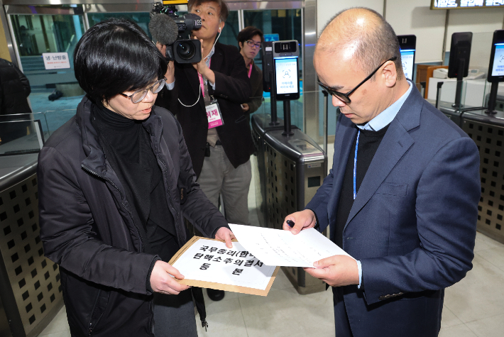 27일 서울 종로구 정부서울청사에서 국회 직원(오른쪽)이 한덕수 국무총리 탄핵소추의결서 등본을 총리실 직원에게 송달하고 있다. 연합뉴스