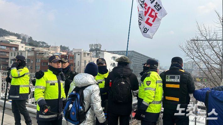 6일 서울 용산구 한남초등학교 인근 육교에서 깃발을 든 시민이 경찰과 대치하고 있다. 박인 기자