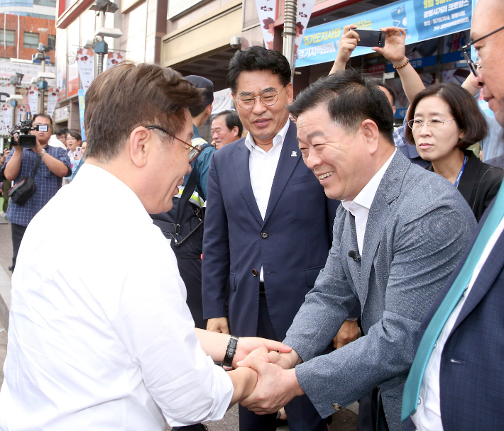 이재명 대표와 박승원 광명시장이 손을 맞잡고 있다. 뒤편에 '경기도지사와 함께하는 경기지역화폐' 현수막이 걸려 있다. 광명시 제공
