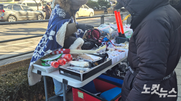 4일 오후 서울 종로구 안국역 5번 출구에서 열린 윤석열 대통령의 탄핵 무효를 주장하는 시위대 옆에서 방한용품이 판매되고 있다. 주보배 기자 