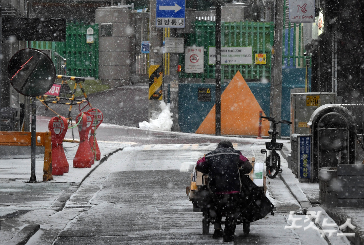 서울 전역에 대설주의보가 내려진 6일 오후 서울 강서구 화곡역 인근에서 한 노인이 눈을 맞으며 폐지 손수레를 밀고 있다. 황진환 기자