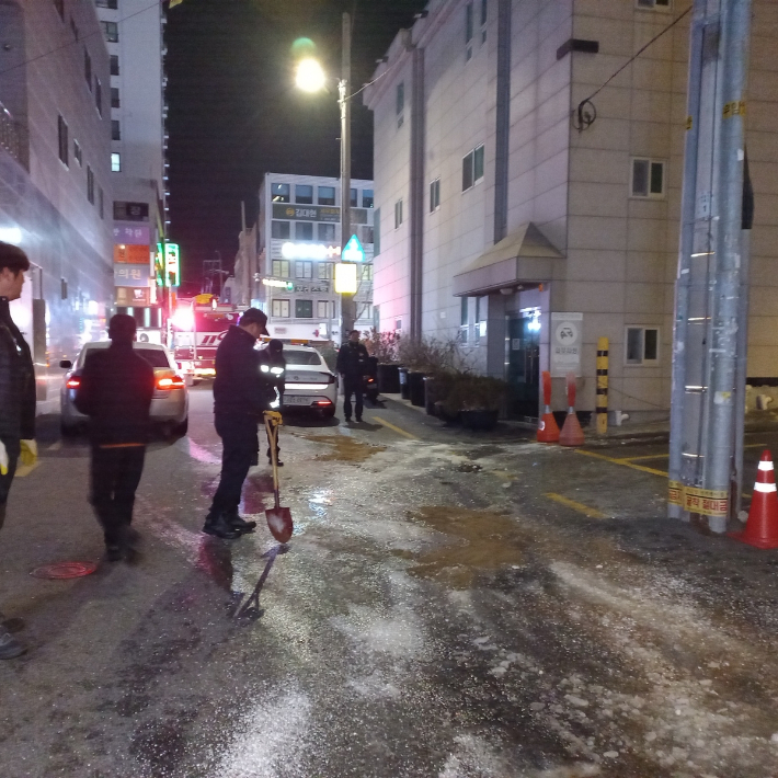 9일 새벽 부산에서 배관 동파로 흘러나온 물리 얼어붙어 소방당국이 흙을 뿌리고 있다. 부산소방본부 제공