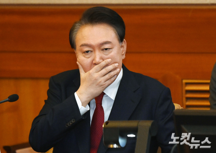 윤석열 대통령이 6일 오전 서울 종로구 헌법재판소 대심판정에서 열린 탄핵심판 6차 변론기일에 출석, 입을 가린 채 변호인에게 말을 하고 있다. 사진공동취재단