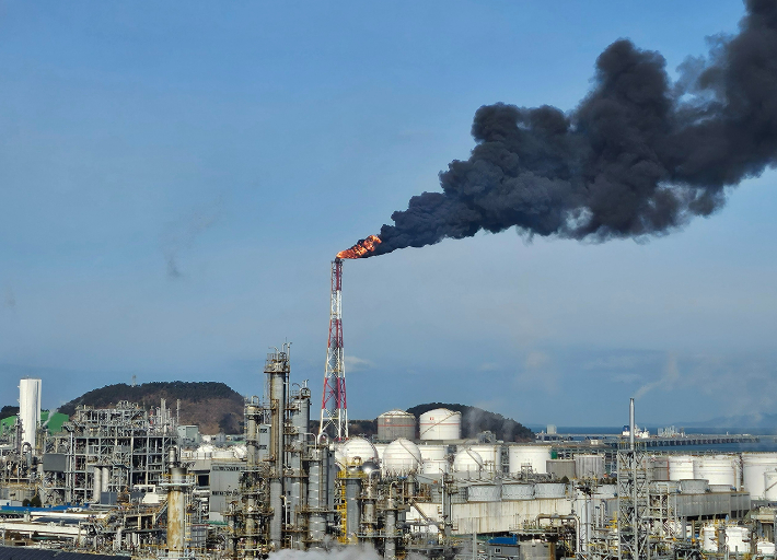 25일 오전 충남 서산 대산석유화학단지 내 LG화학과 롯데케미칼에 전기 공급이 끊기면서 공장 가동이 멈춘 가운데 생산공정에 투입된 원료를 태우는 작업이 진행되면서 굴뚝에서 검은 연기가 뿜어져 나오고 있다.  연합뉴스