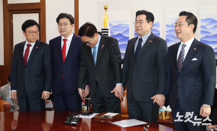 우원식(가운데) 국회의장이 26일 오전 서울 여의도 국회에서 여야 원내대표 회동을 주재하며 양당 원내대표의 손을 잡고 있다. 왼쪽부터 박형수 국민의힘 원내수석부대표, 권성동 원내대표, 우 의장, 박찬대 더불어민주당 원내대표, 박성준 원내수석부대표.