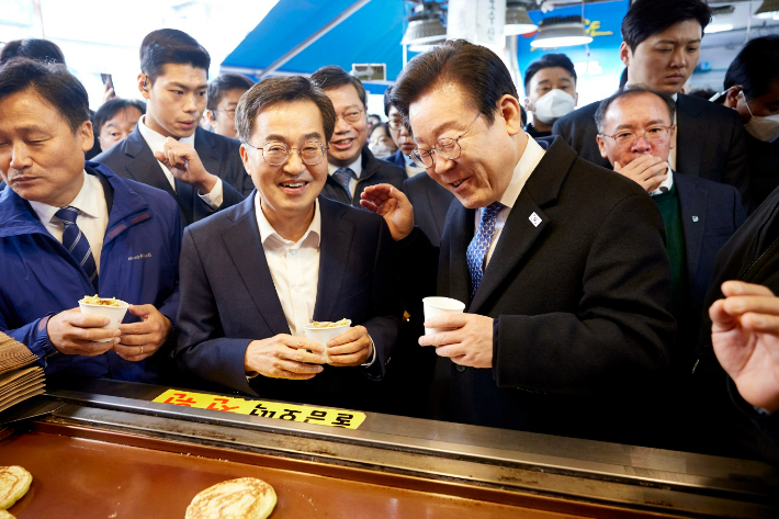 경기 수원시 내 한 전통시장(민생탐방)에서 호떡을 먹으며 환하게 웃고 있는 김 지사와 이 대표. 경기도 제공