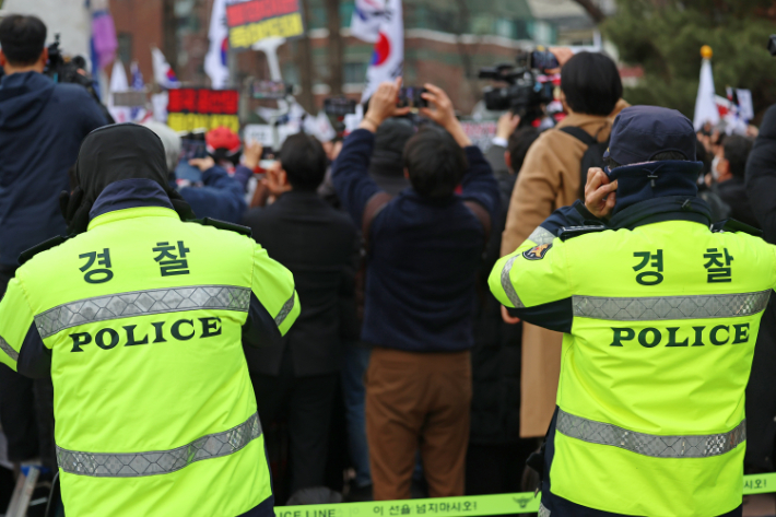 28일 서울 종로구 성균관대학교 앞에서 열린 윤석열 대통령 탄핵 반대 집회 측 스피커 앞에 선 경찰들이 귀를 막고 있다. 연합뉴스