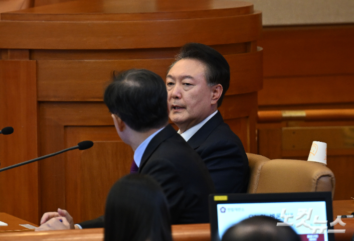 윤석열 대통령이 20일 오후 서울 종로구 헌법재판소에서 열린 탄핵심판 10차 변론에 출석해 윤갑근 변호사와 이야기를 나누고 있다. 사진공동취재단