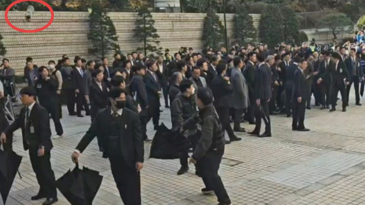 지난해 15일 서울 서초구 서울중앙지방법원에서 더불어민주당 이재명 대표가 공직선거법 위반 사건 1심 선고 공판에 출석할 때 누군가 던진 신발(붉은 원)이 날아들고 있다. 연합뉴스