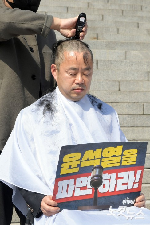 더불어민주당 박홍배 의원이 김문수·전진숙 의원과 11일 서울 여의도 국회 본청 앞에서 윤석열 대통령 조기 파면을 촉구하는 삭발식을 하고 있다.