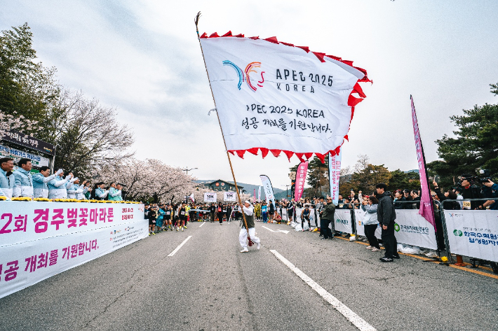 경주벚꽃마라톤대회 출발에 앞서 'APEC 2025 KOREA 성공개최를 기원합니다'라는 내용의 문구가 적힌 대형 깃발 퍼포먼스가 펼쳐지고 있다. 경주시 제공