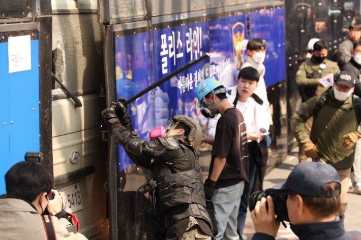 지난 4일 서울 종로구 헌법재판소 인근에서 윤석열 대통령 지지 집회 참가자 중 한 명이 헌재의 윤 대통령 파면 결정에 경찰이 세운 가벽 사이로 보이는 차량을 부수는 모습. 연합뉴스