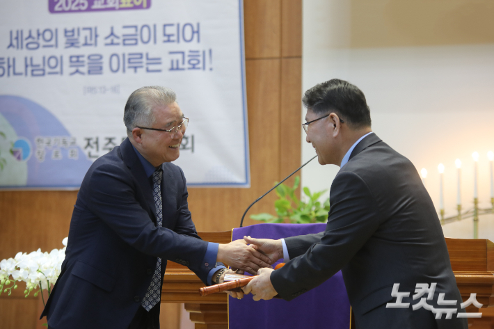 이임하는 조규선 대표회장(왼쪽)이 취임하는 추이엽 대표회장(오른쪽)에게 성경과 의사봉을 전달하고 있다.