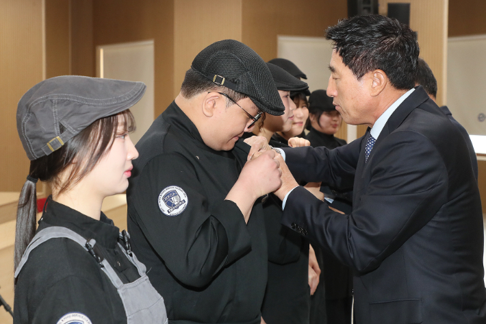 박노준 우석대 총장이 21일 호텔외식조리학과 '2025학년도 신입생 유니폼 착복 및 배지 수여식'에서 한 학생에게 배지를 달아주고 있다. 우석대 제공