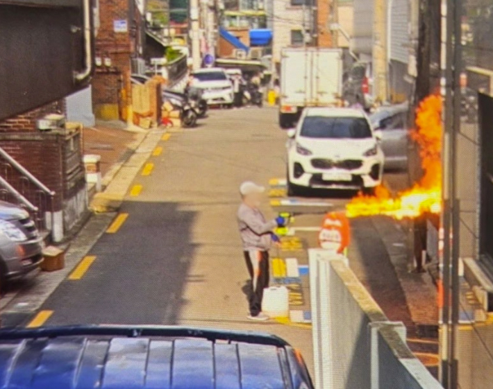 봉천동 아파트 방화 유력 용의자가 21일 서울 관악구 봉천동 한 빌라 앞에서 아파트에 불을 내기 전 농약살포기 추정 도구를 이용해 불을 지르고 있다. 연합뉴스