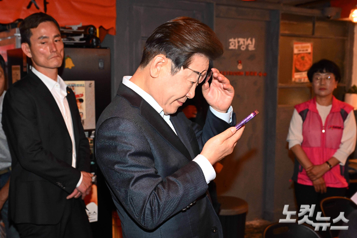 이재명 더불어민주당 대선 후보가 1일 서울 종로구의 한 음식점에서 열린 비전형 노동자 간담회 종료 후 당 관계자에게 전달받은 휴대전화를 확인하고 있다. 황진환 기자