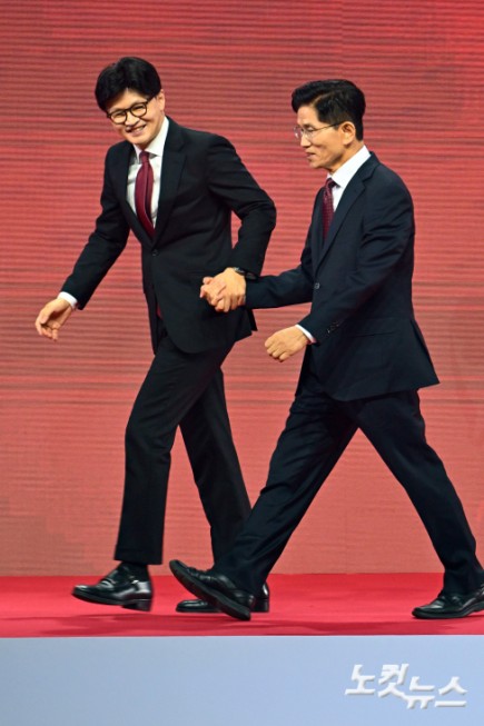3일 경기도 일산 킨텍스에서 열린 국민의힘 제21대 대통령 선거 후보 선출을 위한 제5차 전당대회 무대에서 한동훈·김문수 경선 후보가 인사를 마치고 내려오며 손을 잡고 있다.