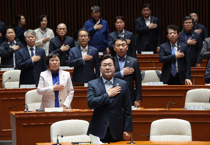 더불어민주당 박찬대 원내대표를 비롯한 의원들이 4일 국회에서 열린 긴급 의원총회에서 국기에 경례를 하고 있다. 연합뉴스