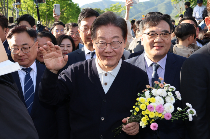 더불어민주당 이재명 대선 후보가 '골목골목 경청투어' : 단양8경편'에 나선 4일 충북 제천군 의림지를 찾아 한 지지자가 준 꽃을 들고 인사하고 있다. 연합뉴스