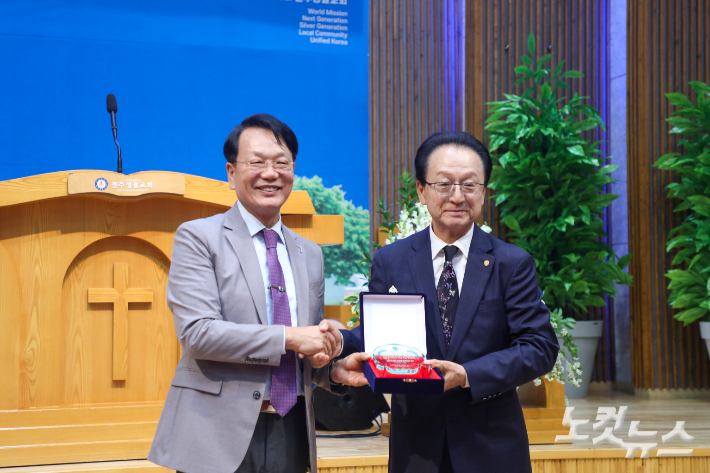 전주성결교회 김복철 목사가 원로장로로 추대 받은  고길성 장로에게  추대패를 전달하고 기념 사진 촬영을 하고 있다.