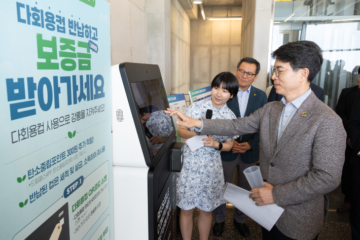  김완섭 환경부 장관이 지난 19일 강원 강릉시 한 카페에서 강릉시 맞춤형 다회용 컵 보증금제 시행을 위한 자발적 협약을 체결, 무인 회수기를 통한 다회용 컵 반납을 시연하고 있다. 환경부 제공    