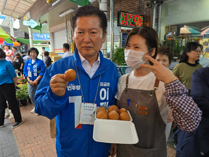정청래 의원이 웃장에서 상인과 함께 도너츠를 들고 기념촬영하고 있다. 고영호 기자